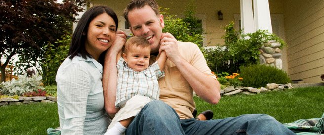 Family smiling in front of home